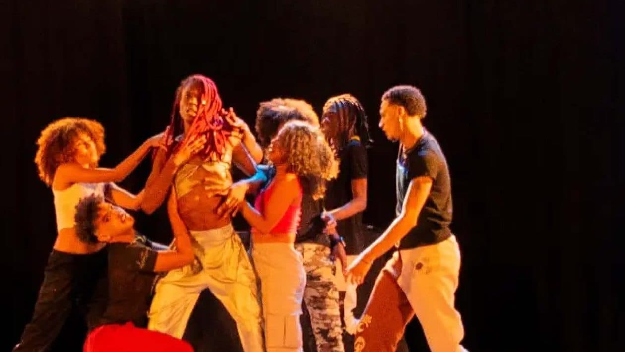Grupo de artistas dançando sob luz quente no palco do Festival FADAS